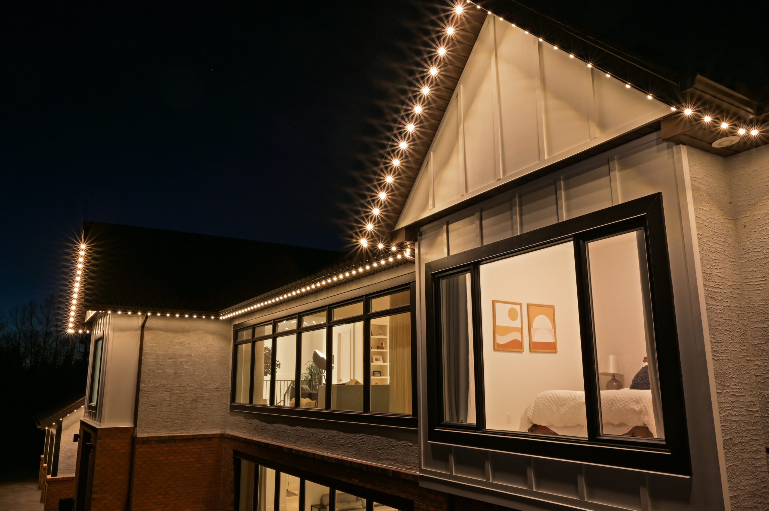 Close-up of evenly spaced warm white permanent lights tracing a gable peak and eaves at night — example from an authorized Gemstone dealer gallery.