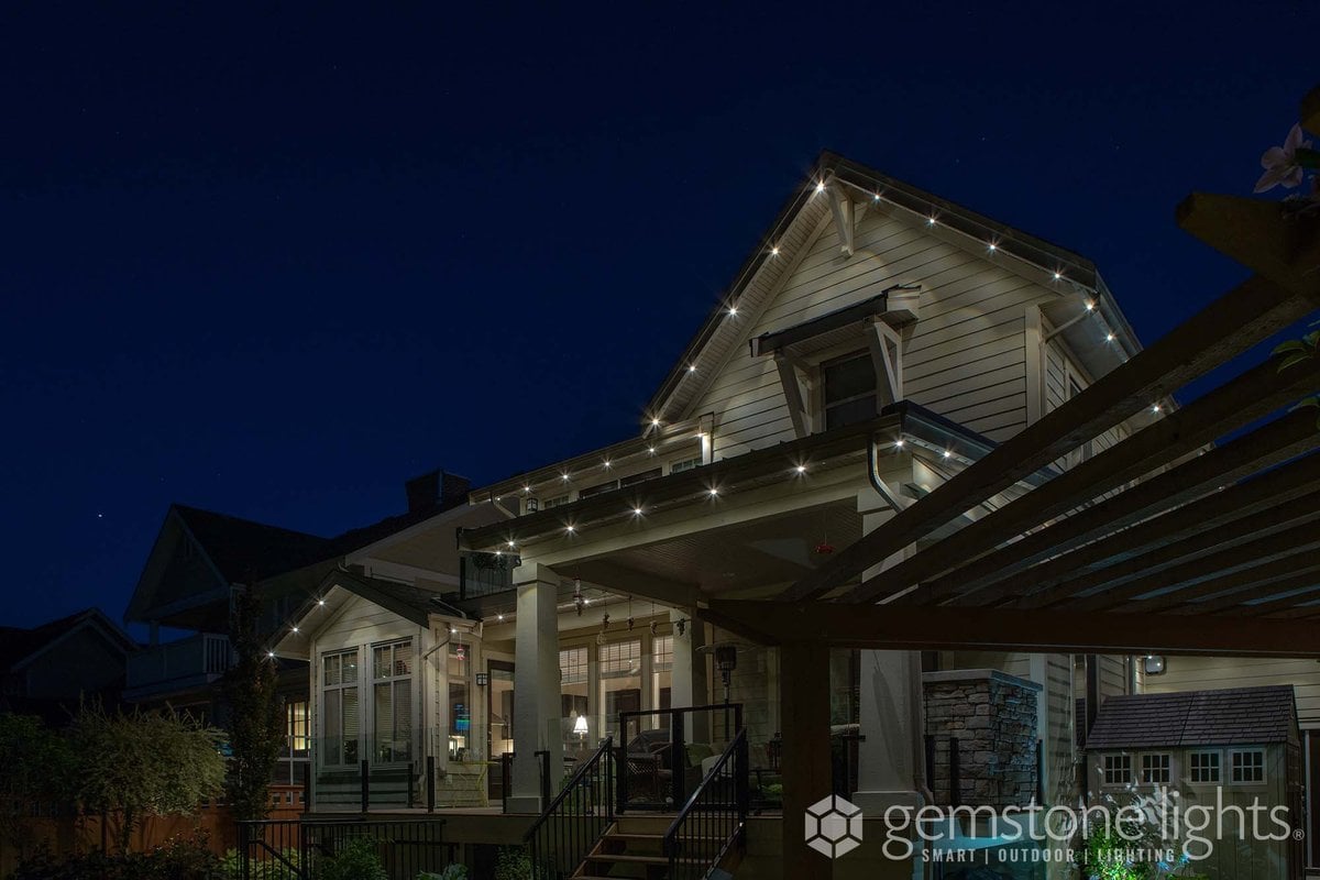 Craftsman home with porch and pergola, accented by Gemstone permanent lighting in white along the rooflines at night