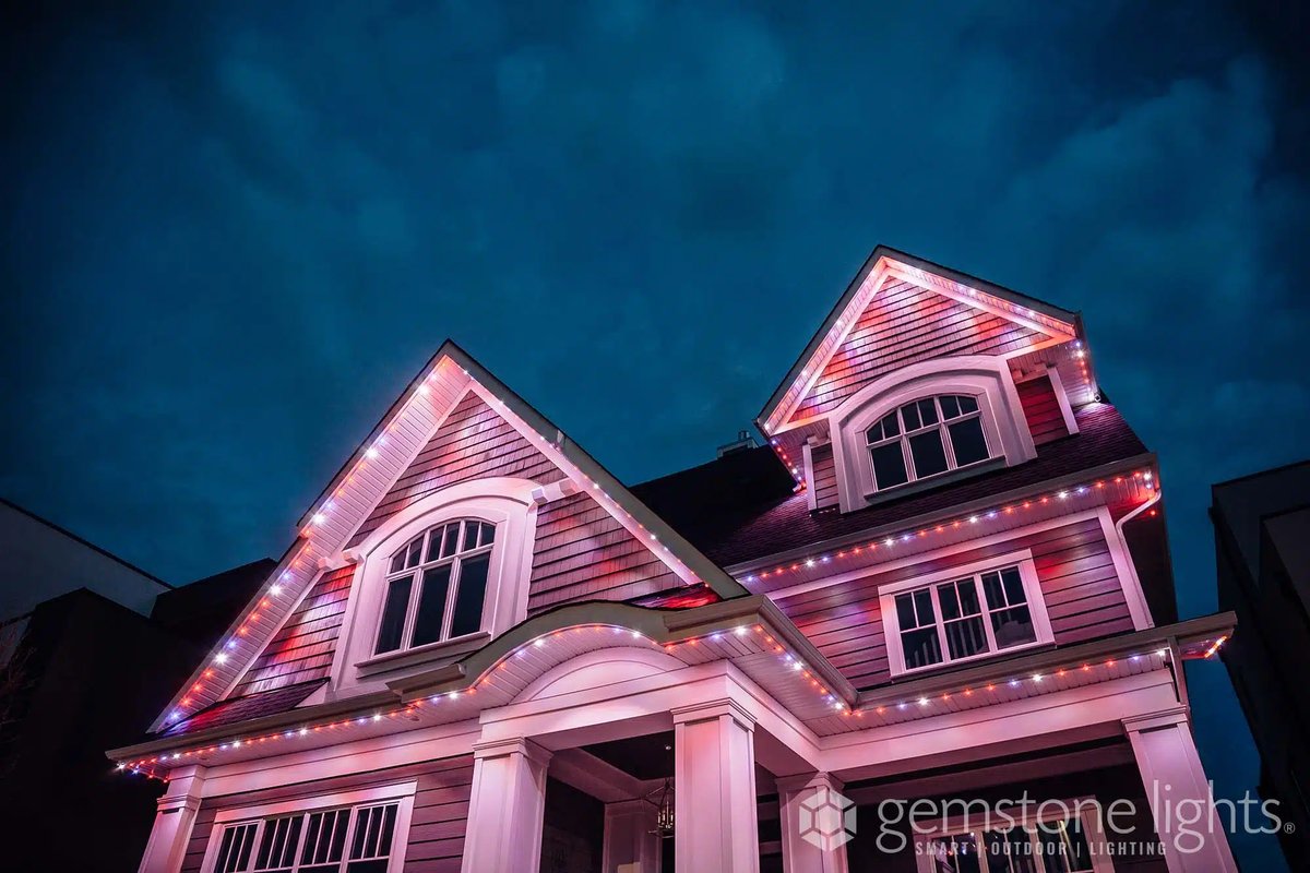 Gabled home lit in pink and white with Gemstone permanent lighting, a holiday color scene
