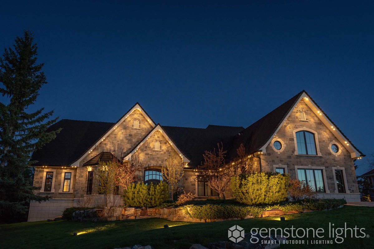 Stone home with Gemstone permanent lighting in warm white tracing its gables at night