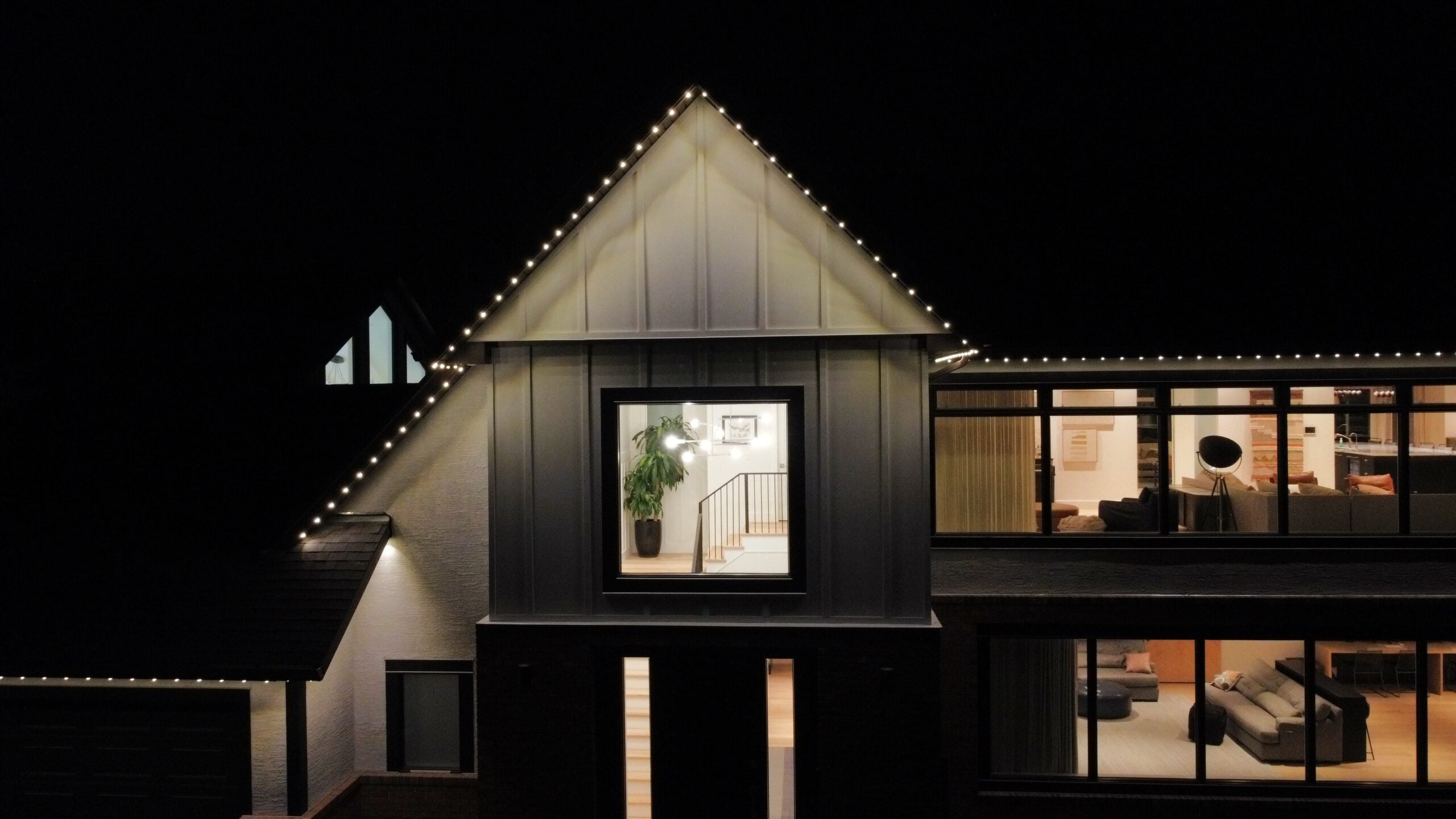 Warm white permanent lights tracing a front gable peak and roofline at night — example from an authorized Gemstone dealer gallery.