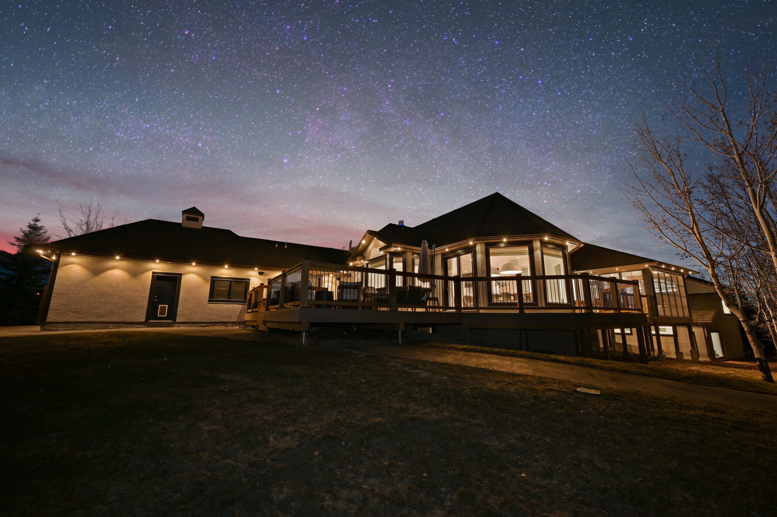 Wide nighttime view of warm white permanent lights along the eaves of a long ranch home and sunroom — example from an authorized Gemstone dealer gallery.