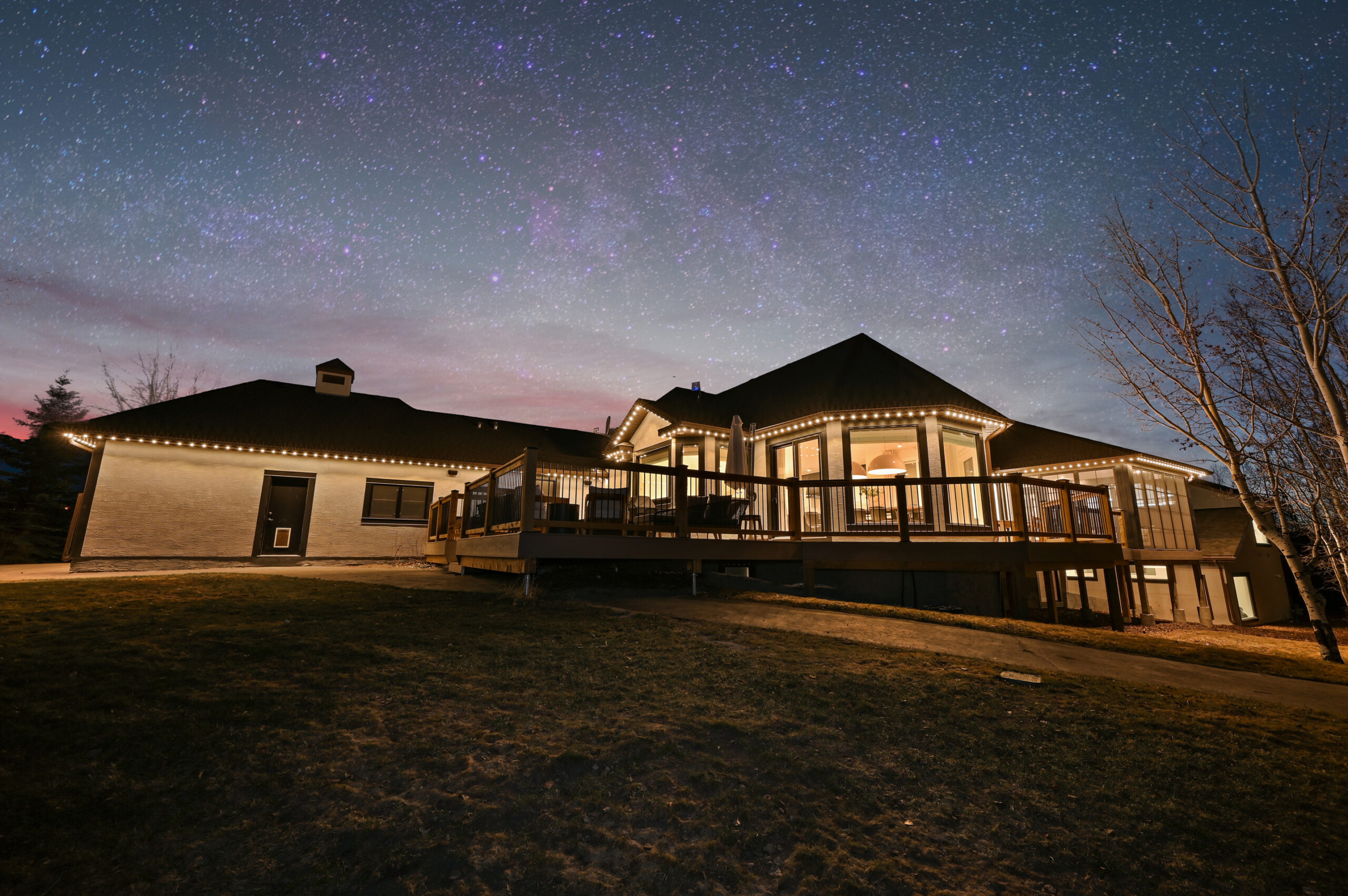 Warm white permanent lighting on the back of a home and deck — an example of extending coverage beyond the front, from an authorized Gemstone dealer gallery.