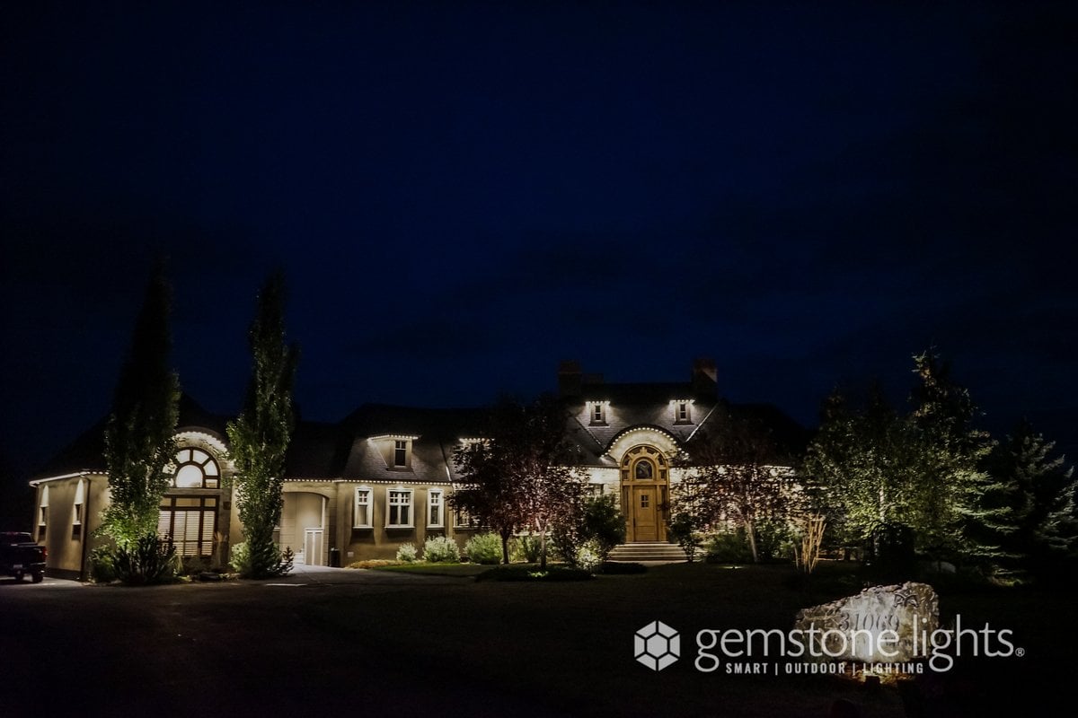 Estate home with Gemstone permanent lighting in warm white on the dormers and arched entry at night