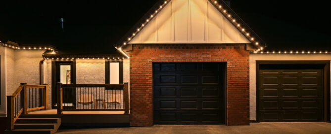Warm white permanent lighting along a gable and garage roofline — example from an authorized Gemstone dealer gallery.